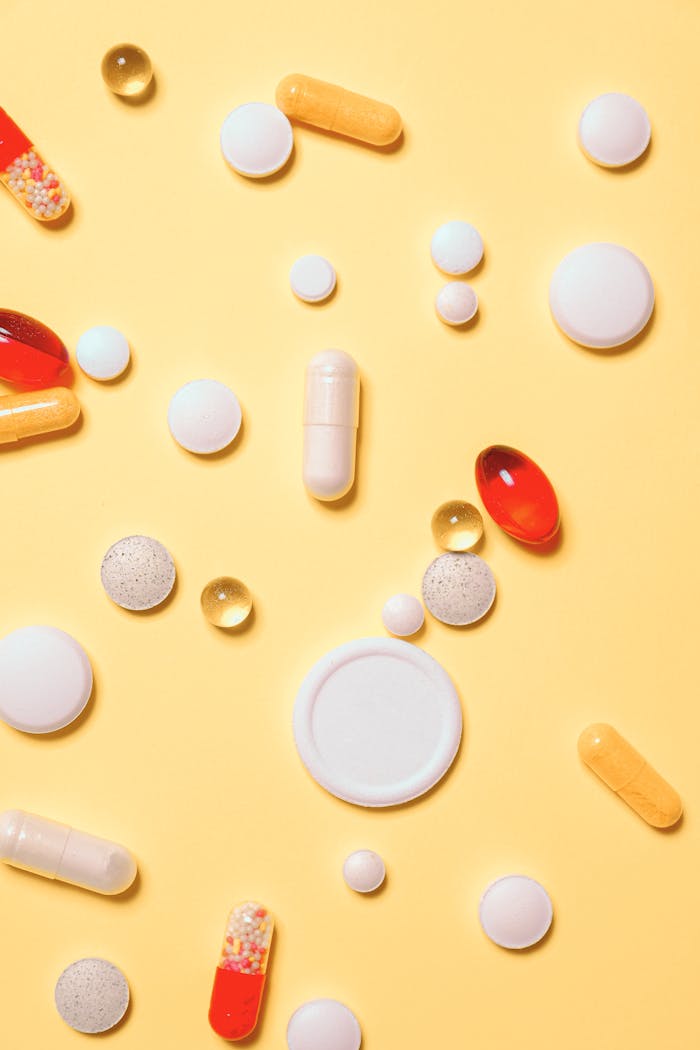 Colorful assortment of pills and capsules on a vibrant yellow background.
